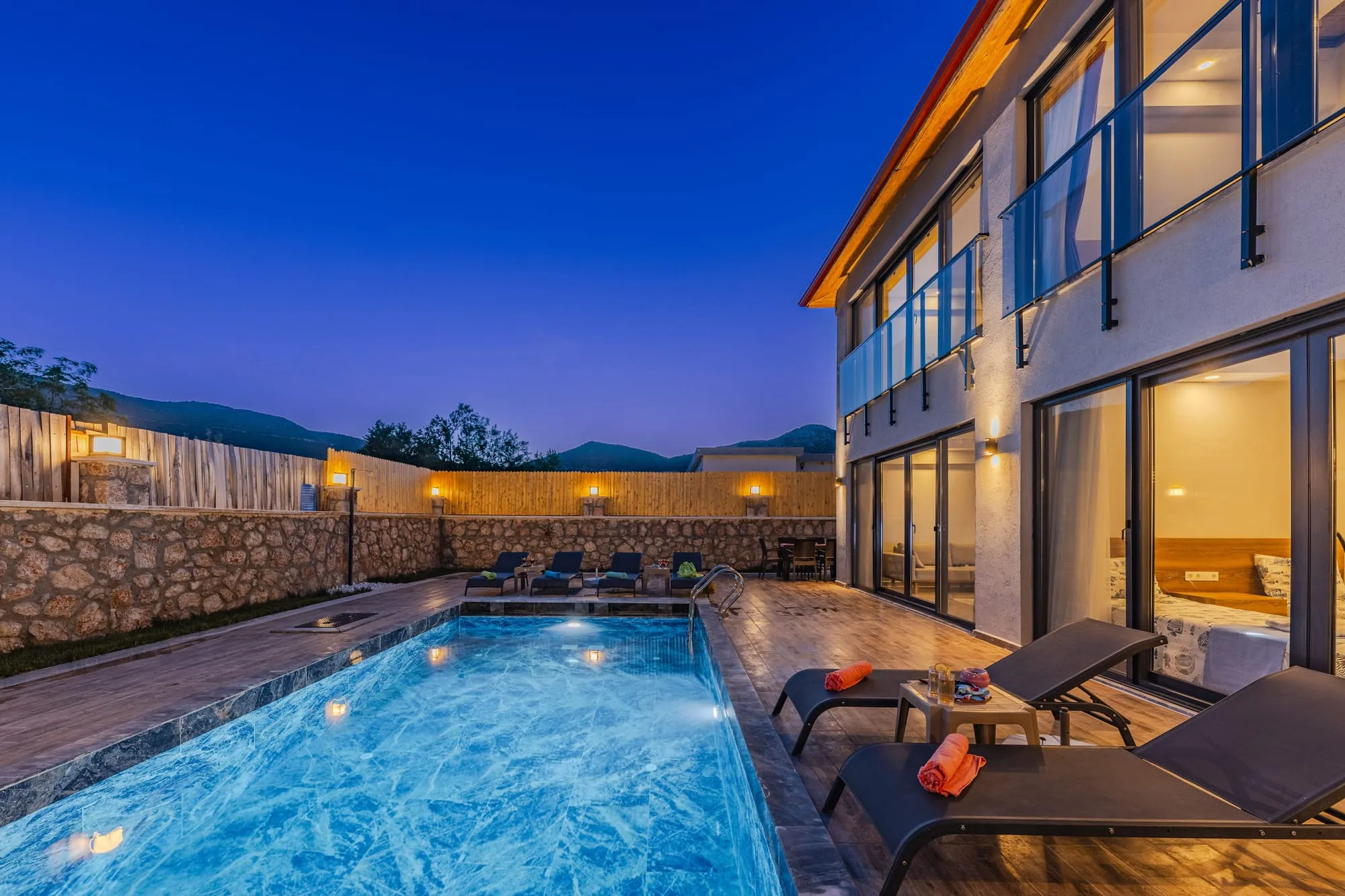 Modern villa with a long pool and lit terraces at dusk