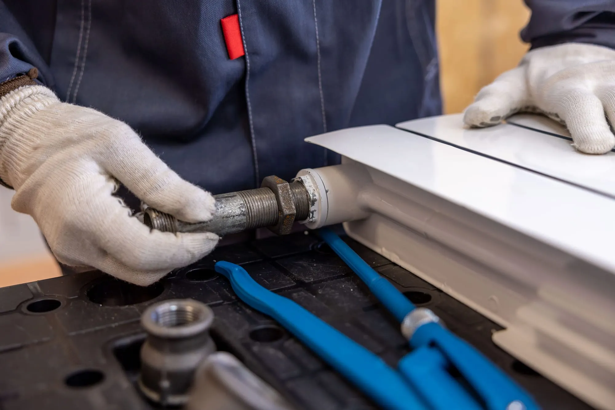 Plumber fitting pipework with gloved hands