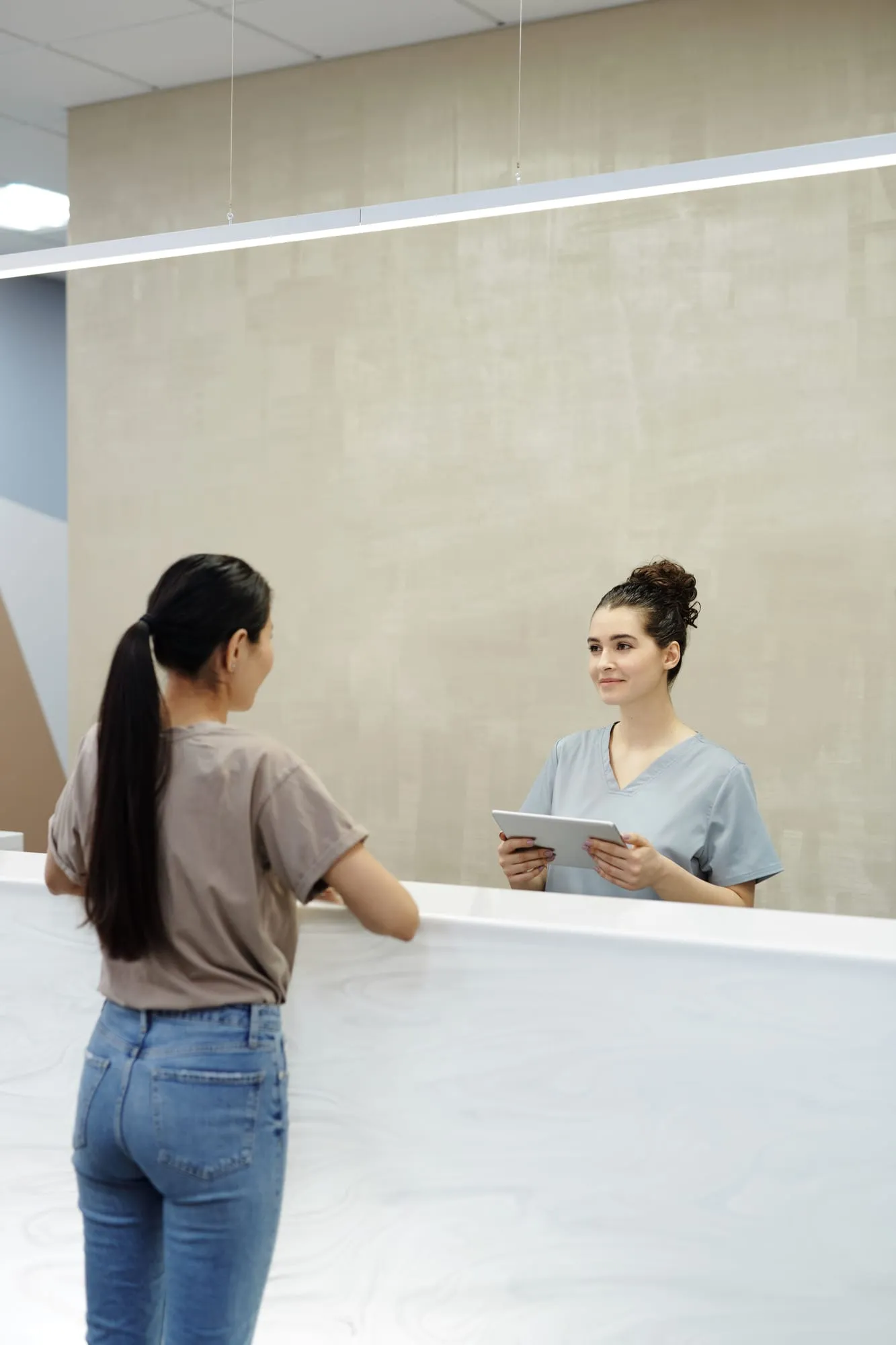 Receptionist welcoming a patient at a bright front desk