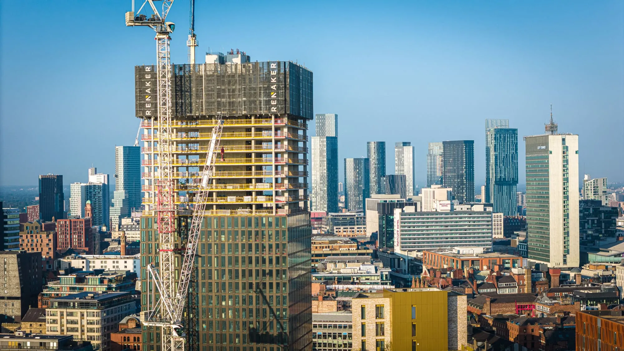 High-rise tower under construction above a city skyline